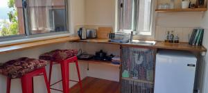 eine Küche mit einer Theke und zwei roten Hockern in der Unterkunft Kaoru on Bruny in Alonnah