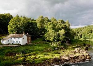 a white house on a hill next to a river at 3 Bed in Lazonby SZ198 in Kirkoswald