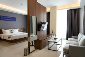 um quarto com uma cama, um sofá e uma televisão em UNHAS HOTEL & CONVENTION em Patjinongong