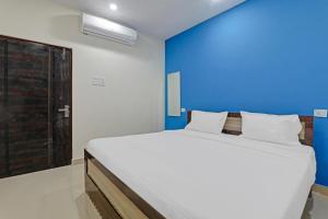 ein Schlafzimmer mit einem großen weißen Bett und einer blauen Wand in der Unterkunft OYO Hotel Rudra Palace Near Phoenix United Lucknow in Charbagh