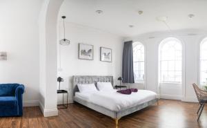Un dormitorio blanco con una cama y una silla azul. en Safestay London Elephant & Castle, en Londres