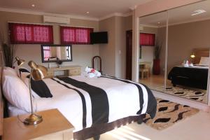 1 dormitorio con 1 cama grande y espejo en Casa Bianca Guest Lodge, en Hartbeespoort