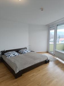 een bed in een witte kamer met een groot raam bij Ferienwohnung INA am Bodensee Uhldingen-Mühlhofen mit Innenpool und Sauna in Uhldingen-Mühlhofen