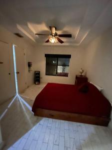 1 dormitorio con cama roja y ventilador de techo en Amplia y céntrica residencia en Reynosa