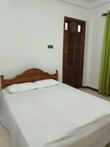 a bed with white sheets and a wooden headboard in a room at white's vila in Matara