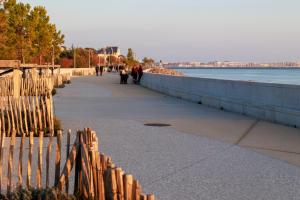 people walking down a sidewalk next to the water at Logis Hôtel Le Rochelois in La Rochelle
