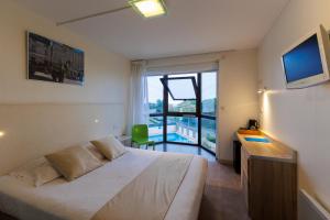 a bedroom with a bed and a desk and a window at Logis Hôtel Le Rochelois in La Rochelle