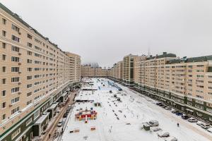a snowy street in a city with tall buildings at Апартаменты 2day apart у Байтерека in Astana