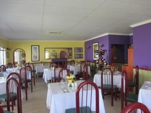 a restaurant with white tables and chairs and purple walls at Casa Bianca Guest Lodge in Hartbeespoort