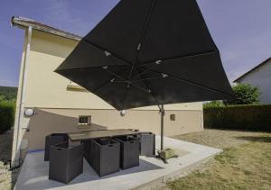 um guarda-chuva preto sobre uma mesa de piquenique e uma grelha em La claire vallee 