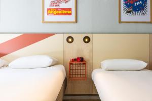 two beds sitting next to each other in a room at ibis budget Angoulême Centre in Angoulême