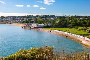 a beach with a fence next to a body of water at Finest Retreats - Atherfield Apartments No 7 - Sunny Side in Paignton