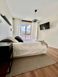 biała sypialnia z dużym łóżkiem i oknem w obiekcie Moderno apartamento inteligente w Madrycie