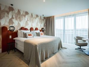 a bedroom with a large bed and a large window at Van der Valk Hotel Dordrecht in Dordrecht