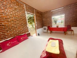 Un dormitorio con una cama y una pared de ladrillo. en Homestay Bách Thảo Tà Lùng, en Phục Hòa