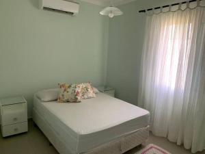 Cama en habitación blanca con ventana en Descanso, pesca e praia, en Iguape