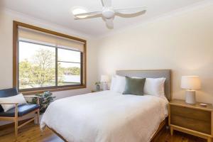 Un dormitorio con una gran cama blanca y una ventana en Byron's Beach House Mylestom en Mylestom