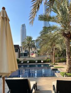 a swimming pool with a umbrella and palm trees at SmartApt Elegant 1 BDR Burj view in Dubai