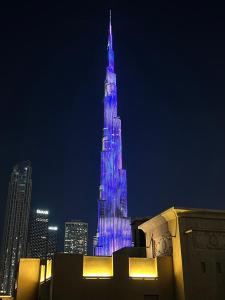 un edificio alto está iluminado de azul en SmartApt Elegant 1 BDR Burj view, en Dubái