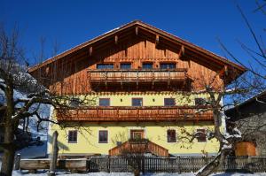 a large building with a wooden roof in the snow at Gästezimmer Peterbauer in Dorfgastein