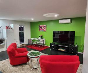 una sala de estar con sillas rojas y una pared verde en Whispering Woods Amore en Maryborough