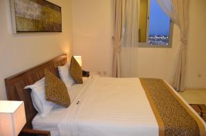 1 dormitorio con 1 cama con sábanas blancas y ventana en السعد للشقق المخدومة, en Al Jubail