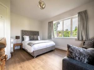 a bedroom with a bed and a couch and a window at Pass the Keys Grand country home with space for all the family in Exeter