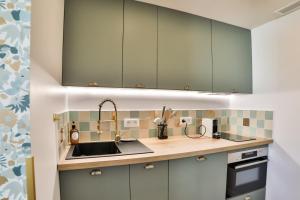 una cocina con armarios verdes y fregadero en Les Voiles - Appart'hotel Le Groix, en Carnac