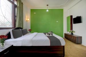 a bedroom with a large bed with a green wall at Capital O Yasmin Resort in Baghwānpur