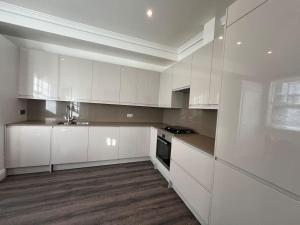 a white kitchen with white cabinets and a sink at Star London Warwick Mansions 3-Bed Oasis in London