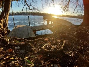 a wooden dock on a lake with the sun setting at Ferienhaus Altes Kabinett in Schorssow
