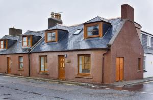 a red brick house with a black roof at Cornerstone Cottage in Laurencekirk
