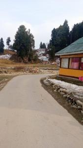 a dirt road next to a house with a building at Gulmarg View Cottage in Gulmarg