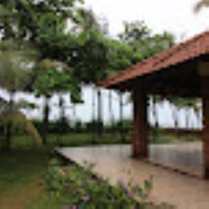 a pavilion in a park with trees and flowers at Coconut Creek Homestay,Kinnigoli in Mūlki