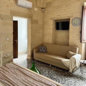 uma sala de estar com um sofá e um relógio na parede em Le Casette nel Borgo em Borgagne