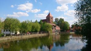 a building next to a river with a church at Ferienwohnung Grapatin in Teterow