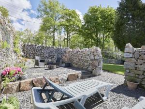 a stone wall with two chairs and a bench at 1 Bed in Eskdale SZ471 in Beckfoot