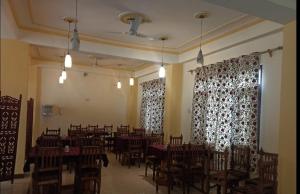 uma sala de jantar com mesas, cadeiras e cortinas em Hotel Mehar Srinagar em Srinagar