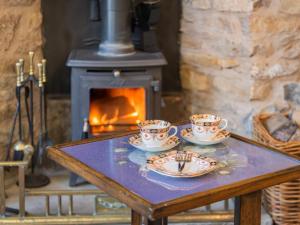 a table with two cups and plates on it with a fireplace at 2 Bed in Kirkby Stephen SZ144 in Kirkby Stephen