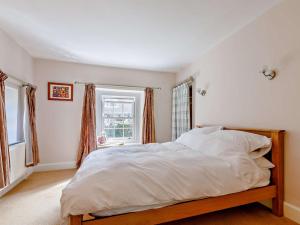 a bedroom with a bed with white sheets and a window at 3 Bed in Bridport 85255 in Puncknowle