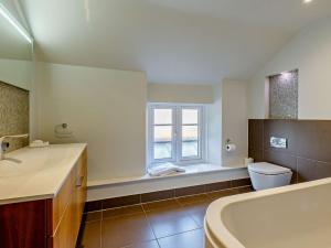 a bathroom with a tub and a toilet and a window at 3 Bed in Bridport 85255 in Puncknowle