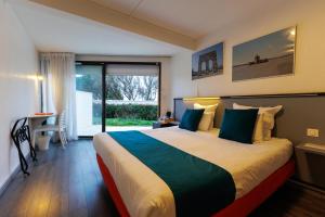 a bedroom with a large bed with blue pillows at Logis Hôtel Le Rochelois in La Rochelle