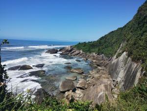 a rocky shoreline with the ocean in the background at Cantinho do descanso in Bertioga