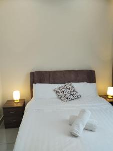 a bedroom with a white bed with two lamps at Amber Cove Leisure Homestay Melaka in Melaka