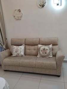 a brown couch with two pillows in a living room at Amber Cove Leisure Homestay Melaka in Melaka