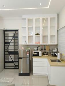 a kitchen with white cabinets and a stainless steel refrigerator at Amber Cove Leisure Homestay Melaka in Melaka