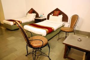 two beds in a room with chairs and a table at Panna Tiger Resort- Riverside Property in Rājgarh