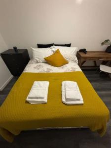 a large yellow bed with two folded towels on it at 2BR/2BA Gem with Private Balcony in London