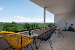 a balcony with chairs and a table with a bottle of wine at Luxury Villa Callista near Labin with kids playground, fitness and heated pool in Ružići