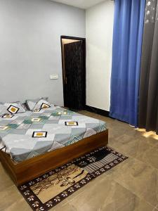 a bedroom with a bed with blue curtains and a rug at The River Side Resort & Farm in Noida